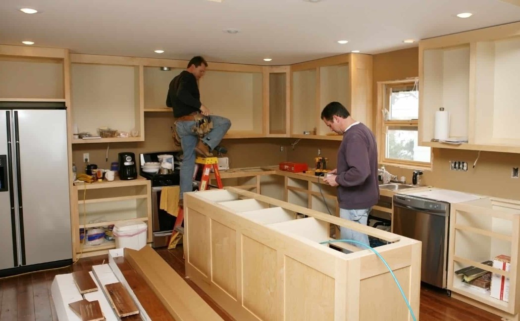 Modern open-concept kitchen renovation featuring white quartz countertops, custom navy cabinets, and pendant lights.